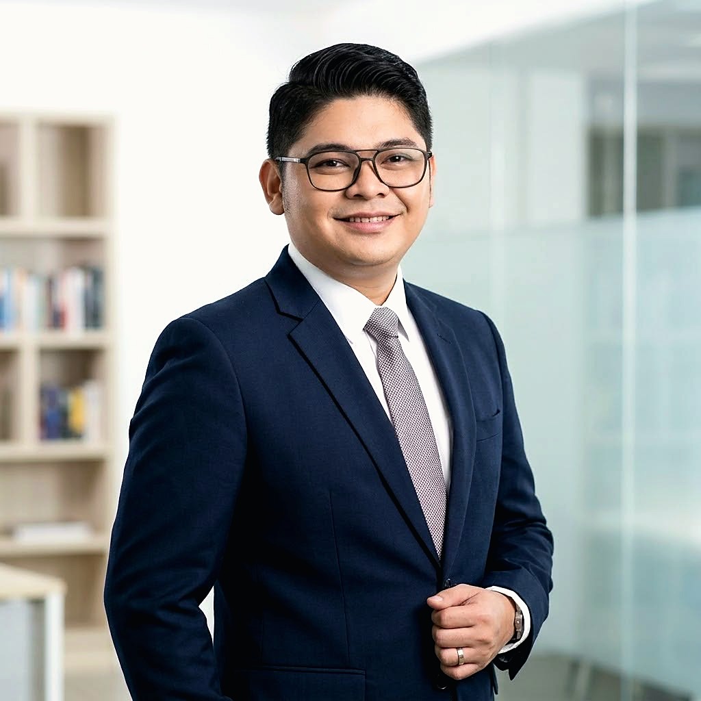 Portrait of Emmanuel Vizconde Alvarez, smiling, wearing glasses and a navy suit